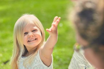 Smiling little girl raising hand to mother