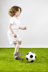 Boy with soccer ball on a gray background.