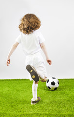 Boy with soccer ball on a gray background. Back view