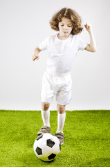 Boy with soccer ball on a gray background.