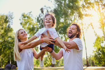 Happy family playing with a child in the park.