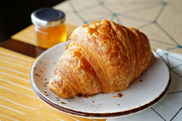 Closeup of fresh baked croissants on ceramic plate with orange jam. Selective focus for designed work. Breakfast with bakery in the morning