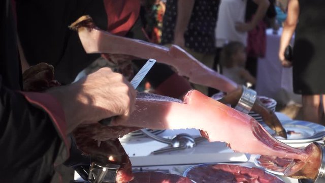 Professional cutting serrano ham leg in slow motion