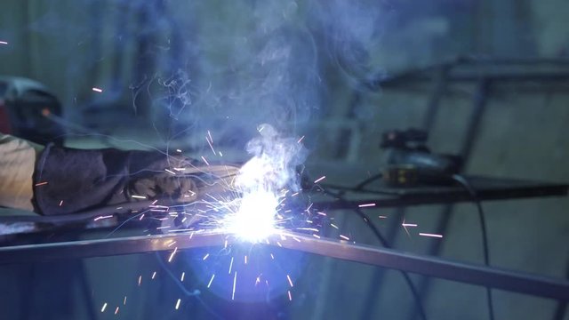 Welder welding a metal in workshop. Slow Motion.