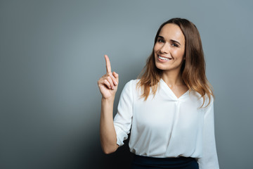Joyful happy woman pointing up with her finger