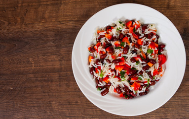 rice with red beans and vegetables on wooden table. with copy space. top view.