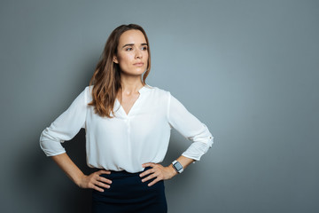 Serious smart businesswoman resting hands on her hips - obrazy, fototapety, plakaty