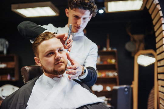 Man hairdresser doing haircut beard adult men in the men's hair salon