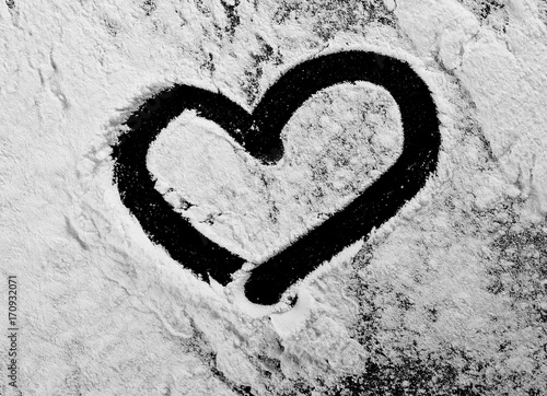 Pile of wheat flour heart shape isolated on black background, powder texture, top view with clipping path