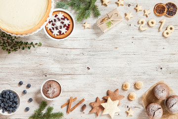 New year preparation concept. Christmass background with berries, cake and gift. New Year composition with snowflakes, sweets, cinnamon, number year 2018 on a beige wooden background.