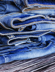 stack of jeans lying on a wooden table