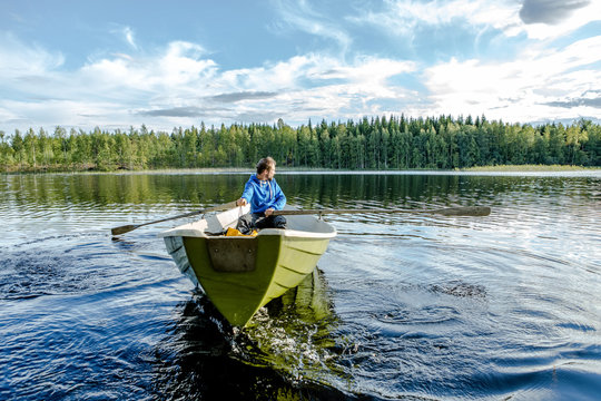 Finnland, leben im M&ouml;kki, auf einer Insel die nur mit dem Ruderboot zu erreichen ist. Der n&auml;chste Ort Juvola ist 1 km entfernt. Region Linnansaari Nationalpark, Ein Mann rudert &uuml;ber den See