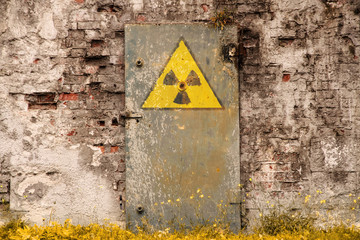 Radioactive (ionizing radiation) danger symbol painted on the old massive rusted iron door of an...