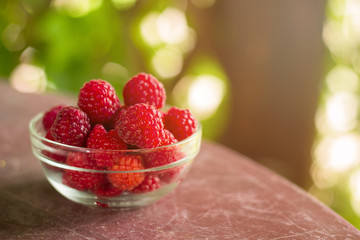 fresh raspberries in a glass bowl on a table in a gazebo