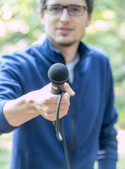 Journalist mit Mikrofon, draußen, Unschärfe