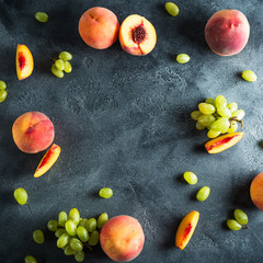 Sliced peaches and green grapes on dark table. Fruit frame concept. Flat lay, top view