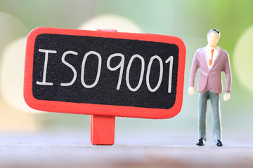 Businessman stand near wooden sign of ISO9001 Text.