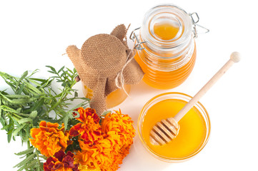 Natural honey in jar and dipper with flowers on a white background