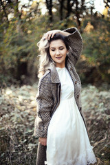 Outdoors portrait of a young woman. Autumn look: white dress and beige coat. Tirana Grand Park.