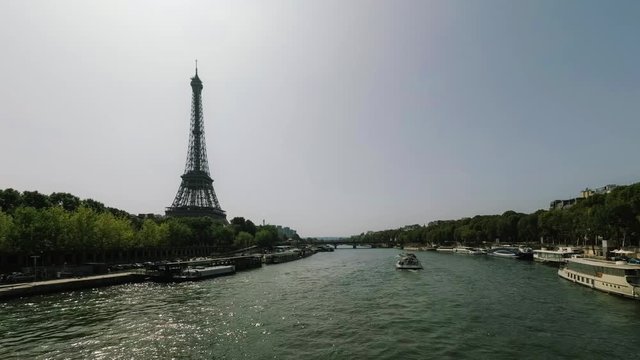 River boats and street traffic time lapse near the Eiffel tower during rush hours in Paris, France. Summer cityscape, city life, vacation and touristic places in Europe. Transport and tourism concept