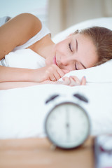 A young woman putting her alarm clock off in the morning.