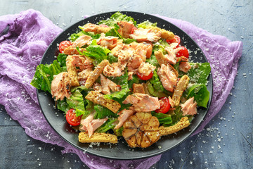Cesar salad with salmon, cherry tomatoes, garlic, crutons, romaine lettuce and parmesan.