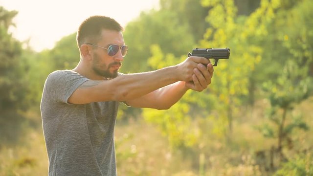 Young man is shooting from a gun, close up