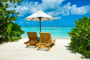 Beautiful sandy beach with sunbeds and umbrellas in Indian ocean, Maldives island