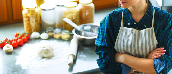 Beautiful woman cooking cake in kitchen standing near desk