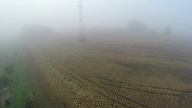Drone fly up high in misty summer morning over farmland landscape, aerial view