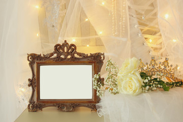 Old vintage oval mirror and beautiful white wedding dress and veil on chair with gold garland lights