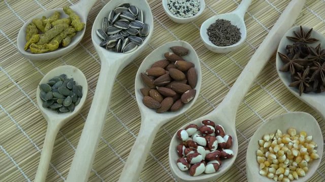 Wooden spoons with various vegetables, spice and nuts, rotating food background