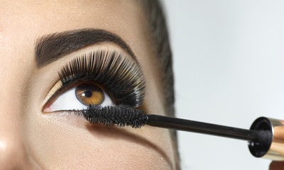 Long lashes closeup. Beautiful woman applying mascara on her eyes. Makeup