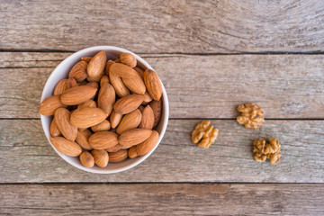 White ceramic bowl with almond on the wooden background