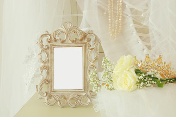 Old vintage oval mirror and beautiful white wedding dress and veil on chair © tomertu