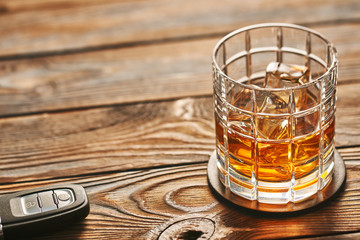 Glass of whiskey or alcohol drink with ice cubes and car key. Drink and drive concept.