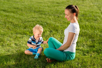 Naklejka na ściany i meble Happy woman and child having fun outdoor on meadow
