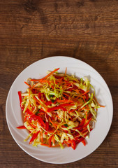 fresh vegetables salad with cabbage and carrot on wooden table. with copy space. top view.