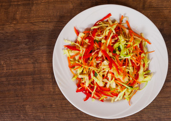 fresh vegetables salad with cabbage and carrot on wooden table. with copy space. top view.