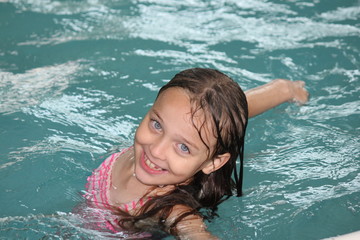 Young girl-child playing around, having fun in a swimming pool.  