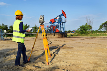 A female engineer - land surveyor at work on an European oil well