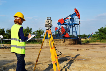A female engineer - land surveyor at work on an European oil well