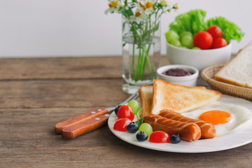 Homemade breakfast with sunny side up fried egg toast sausage fruits vegetable strawberry jam and orange juice in side view with copy space.Delicious homemade american breakfast concept for background