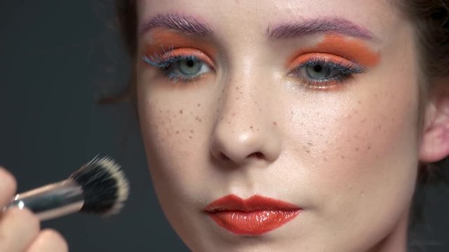 Visagist using brush close up. Face makeup, bright colors.