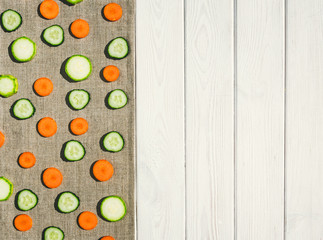 Sliced summer vegetables and a linen tablecloth. Background for the menu