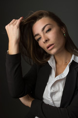 High fashion portrait of young elegant sexy slim brunette woman posing in studio wearing fashionable black jacket suit and white shirt.