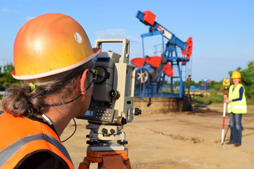 Two engineers - land surveyors at work on an European oil well   
