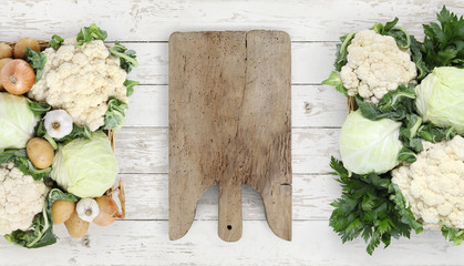 Healthy eating concept wooden cutting board with basket vegetables cabbage and cauliflower on kitchen white worktop, copy space, top view