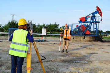Two engineers - land surveyors at work on an European oil well   