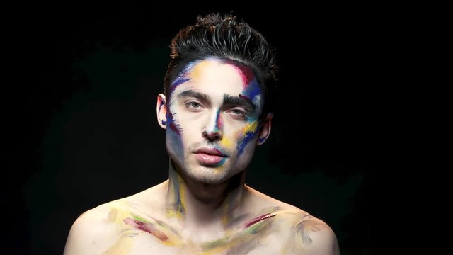 Handsome guy, makeup art. Young man on black background. The living palette.